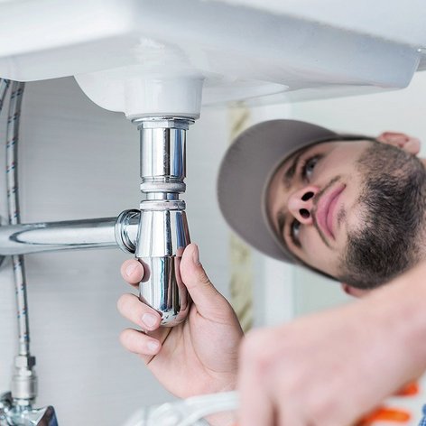 Ein Monteur unter einem Waschbecken 
